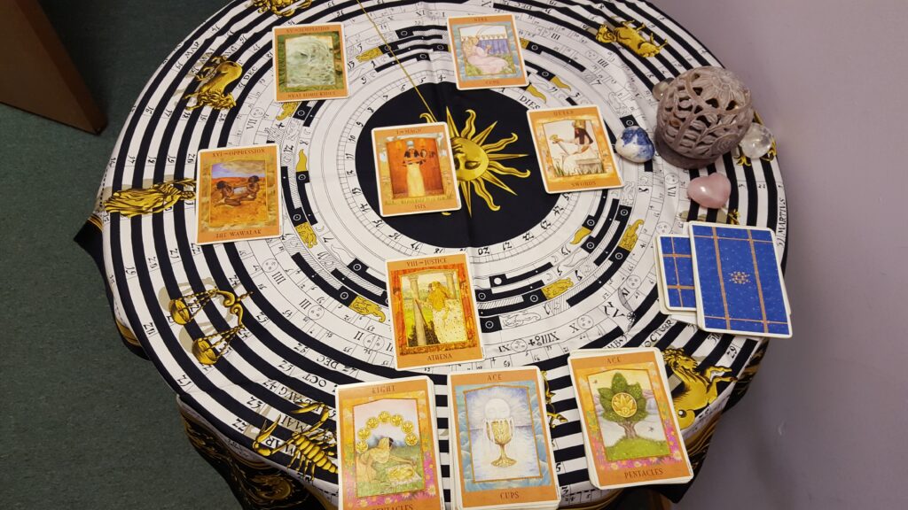 tarot cards spread out on a cloth with astrological symbols on it